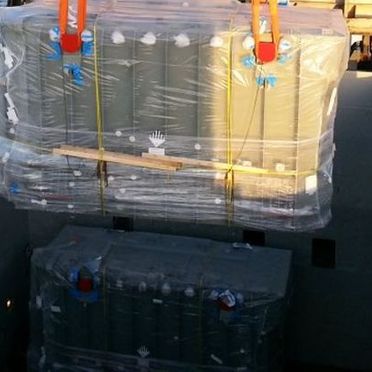 Arbeidere i verneutstyr som ser over en last som er i en container ved havet